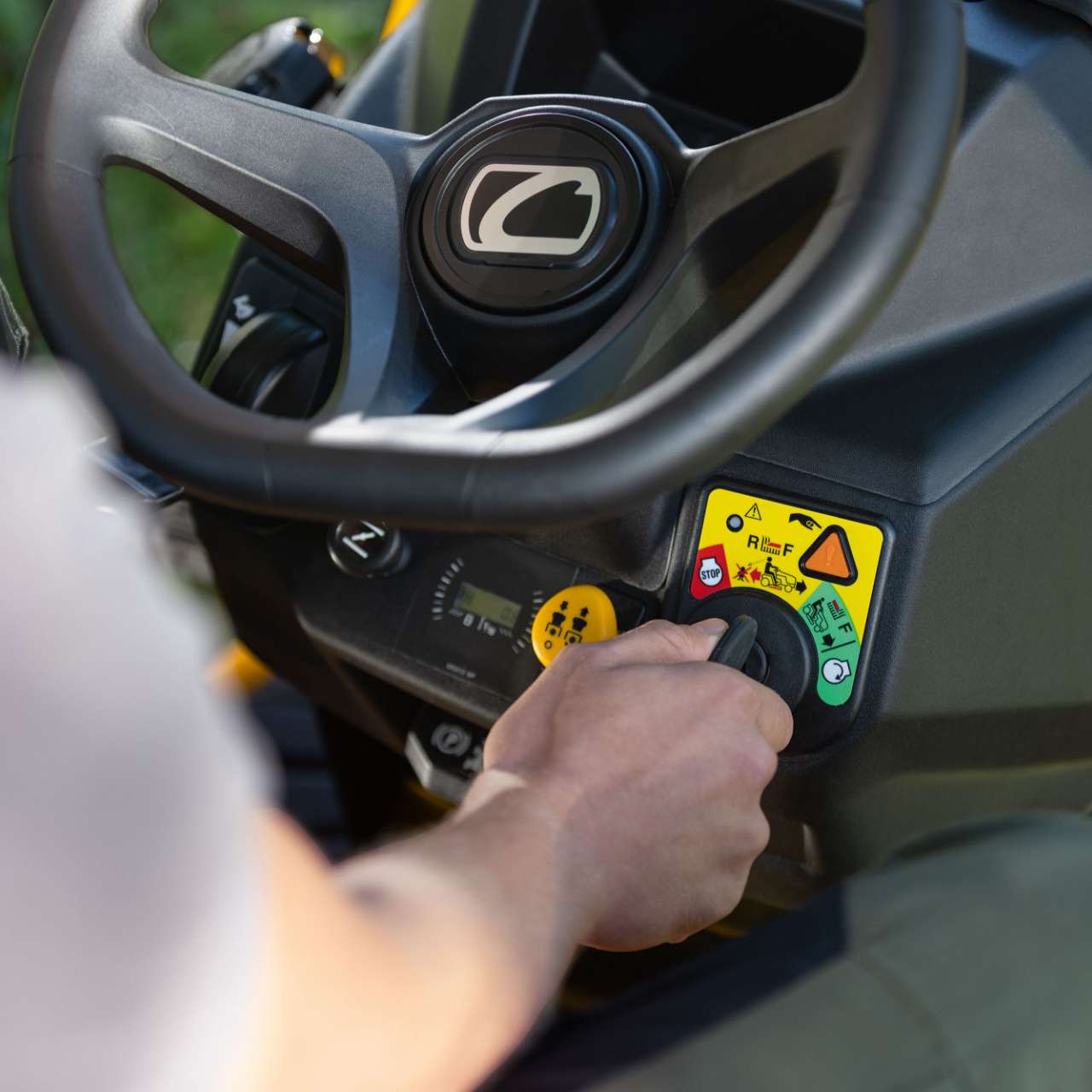 Nahaufnahme der Bedienelemente eines Cub Cadet Rasentraktors – eine Hand betätigt den Schalter.