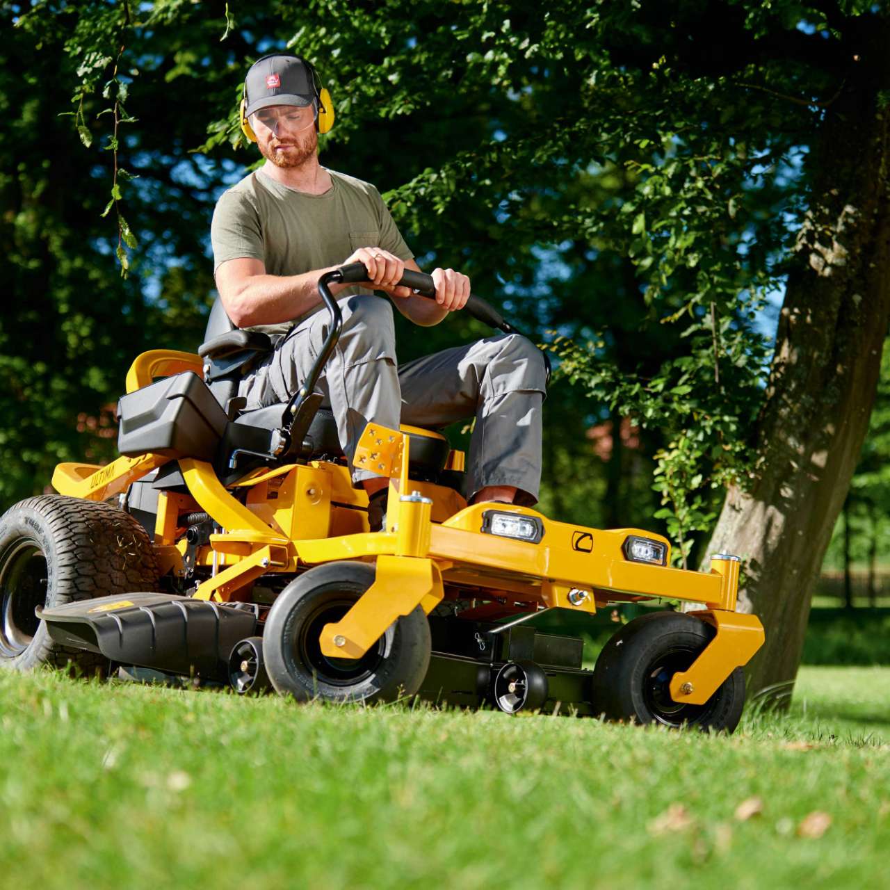 Mann fährt mit einem Cub Cadet Zero-Turn-Mäher über eine Wiese – Einsatz im Grünen.