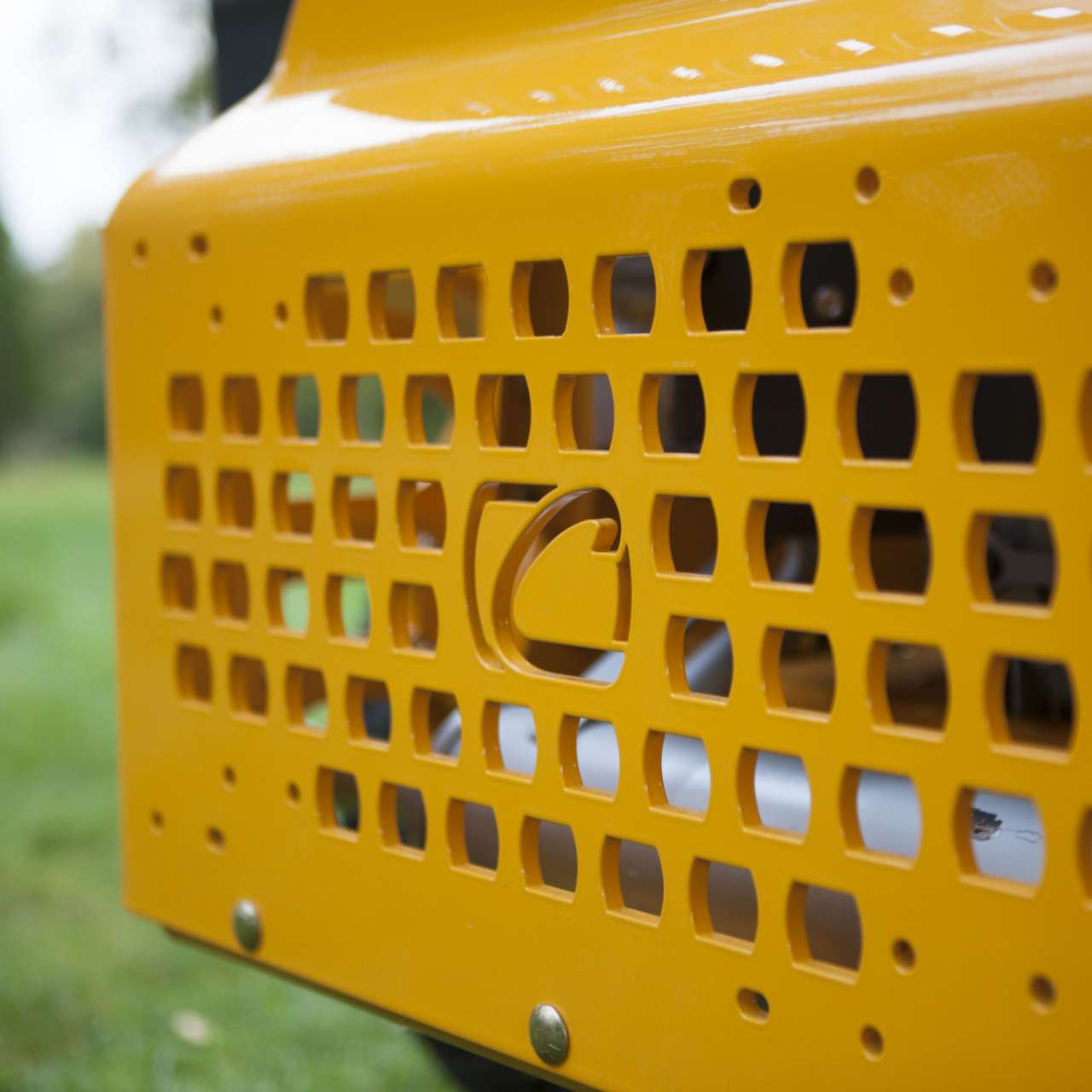 Nahaufnahme eines gelochten Gelbmetall-Gitters mit eingestanztem Cub Cadet Logo.